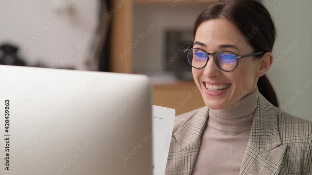 A happy businesswoman is working with a computer while sitting in the office A happy businesswoman is working with a computer while sitting in the office