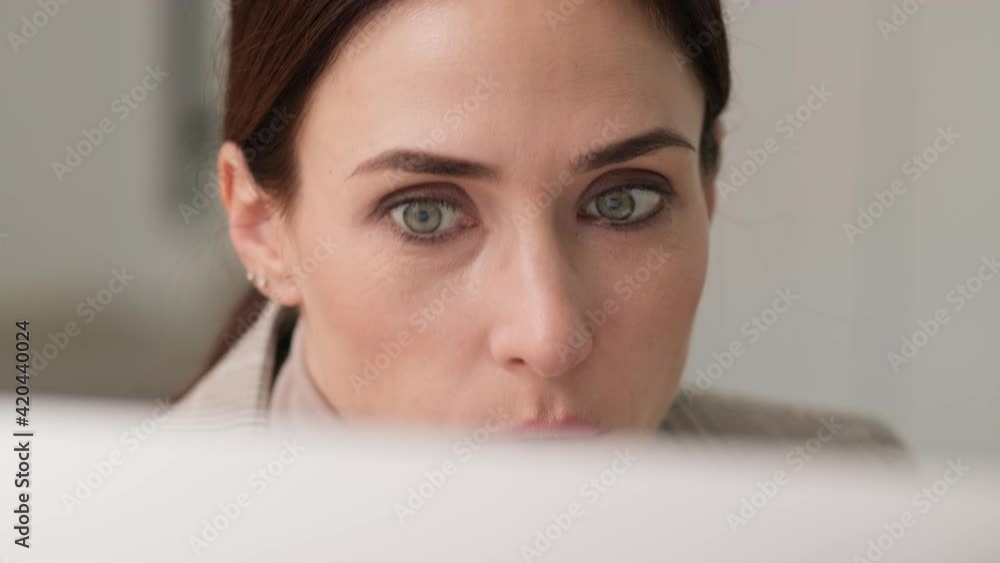 A cropped view of a serious businesswoman is talking with a video-connection using her computer sitting in the office A cropped view of a serious businesswoman is talking with a video-connection using her computer sitting in the office