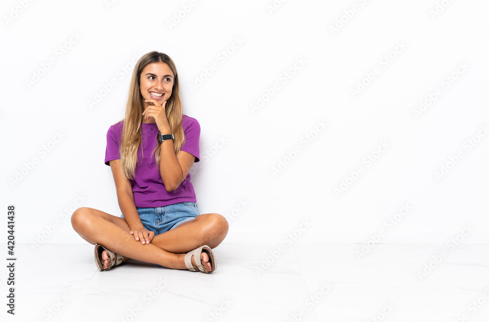 Young hispanic woman sitting on the floor looking to the side and smiling Young hispanic woman sitting on the floor looking to the side and smiling