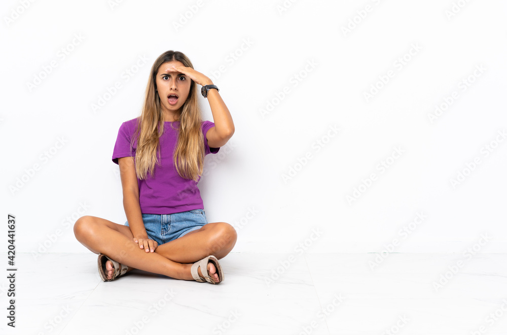 Young hispanic woman sitting on the floor doing surprise gesture while looking to the side Young hispanic woman sitting on the floor doing surprise gesture while looking to the side
