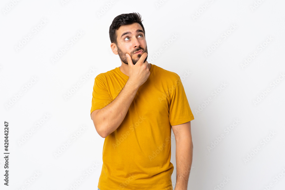 Young handsome man with beard isolated on white background having doubts and with confuse face expression Young handsome man with beard isolated on white background having doubts and with confuse face expression