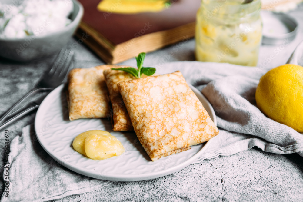 Crepes with homemade cottage cheese and lemon curd on a gray plate