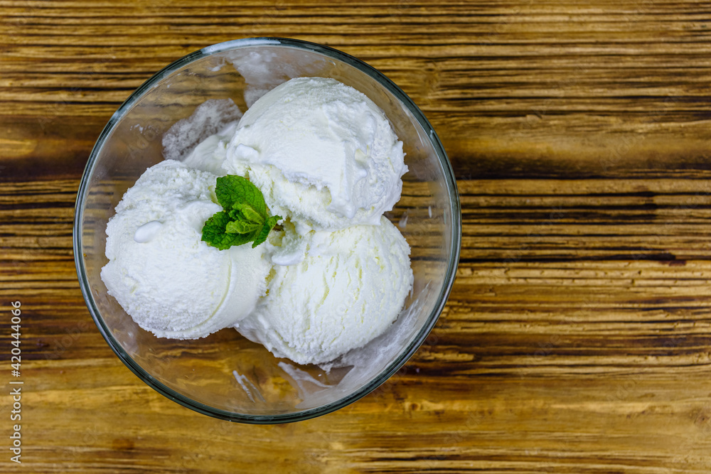 Glass bowl with ice cream balls and mint leaf on a wooden table. Top view Glass bowl with ice cream balls and mint leaf on a wooden table. Top view