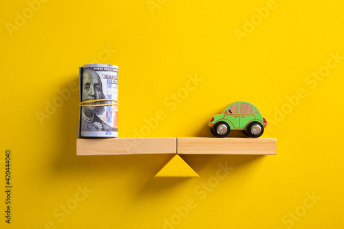 Car / Auto loan or transforming assets into cash concept : Car model, US dollar notes in jute bags on simple balance scale, depicts car owner or borrower turns personal properties into cash.