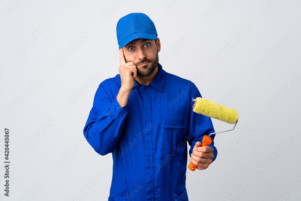 Painter man holding a paint roller isolated on white background thinking an idea