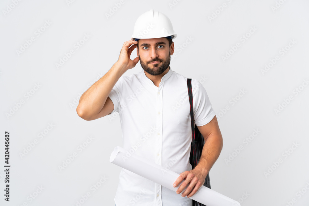 Young architect man with helmet and holding blueprints isolated on white background with an expression of frustration and not understanding Young architect man with helmet and holding blueprints isolated on white background with an expression of frustration and not understanding