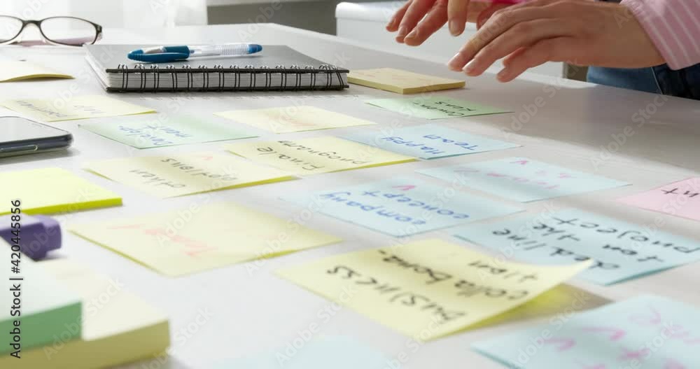 Business woman working on a project using sticky notes on her desktop. Brainstorming to find new development ideas and company strategies. Business woman working on a project using sticky notes on her desktop. Brainstorming to find new development ideas and company strategies.