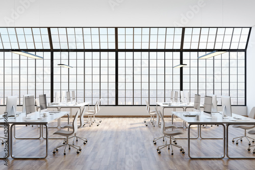 Sunny open space office with huge sqaured window, white furniture with modern computers and wooden floor