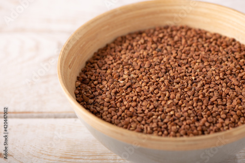 buckwheat groats in a wooden plate on a wooden background close up