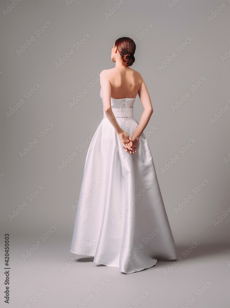 White wedding dress. Studio portrait of beautiful young bride posing and looking to the camera. Classic wedding style. Marriage day. White wedding dress. Studio portrait of beautiful young bride posing and looking to the camera. Classic wedding style. Marriage day.