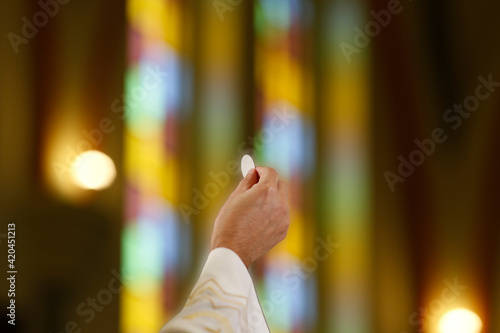 Priest hand holding a host in Catholic celebration