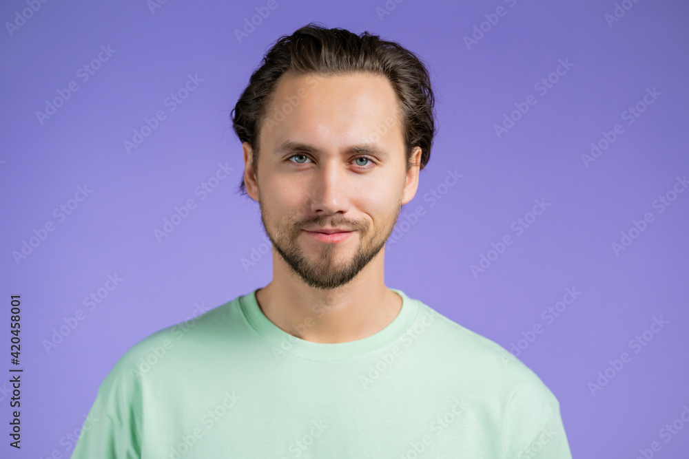 Fototapeta premium Portrait of cheerful european man looking to camera.Young handsome kind guy smiling in studio on violet background.