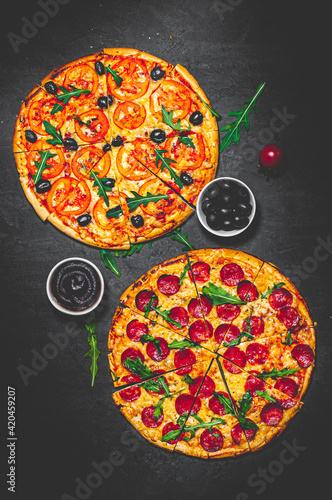 Pepperoni Pizza and Pizza with Mozzarella cheese, Tomatoes, pepper, olive, Spices and Fresh arugula. Pizza Margherita or Margarita on Dark grey black slate background
