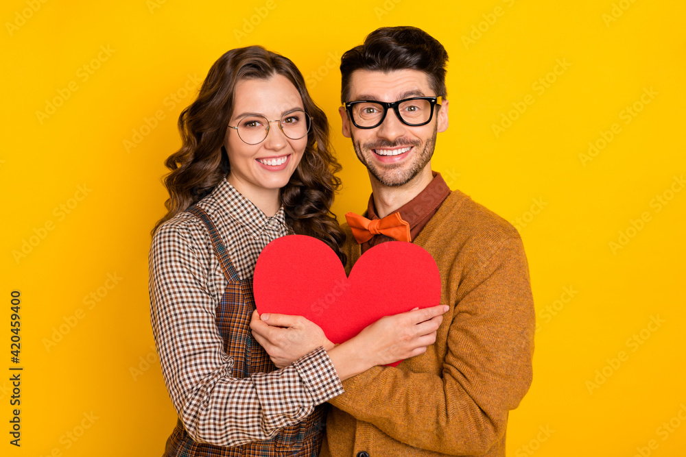 Portrait of attractive cheerful careful amorous couple embracing holding heart shape form figure isolated on bright yellow color background