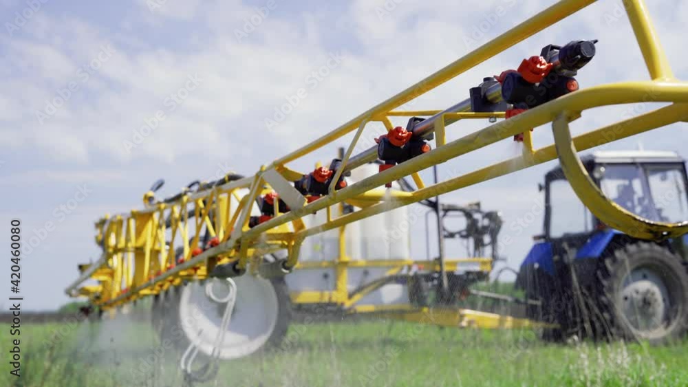 Spraying wheat crops field with tractor and sprayer Spraying wheat crops field with tractor and sprayer