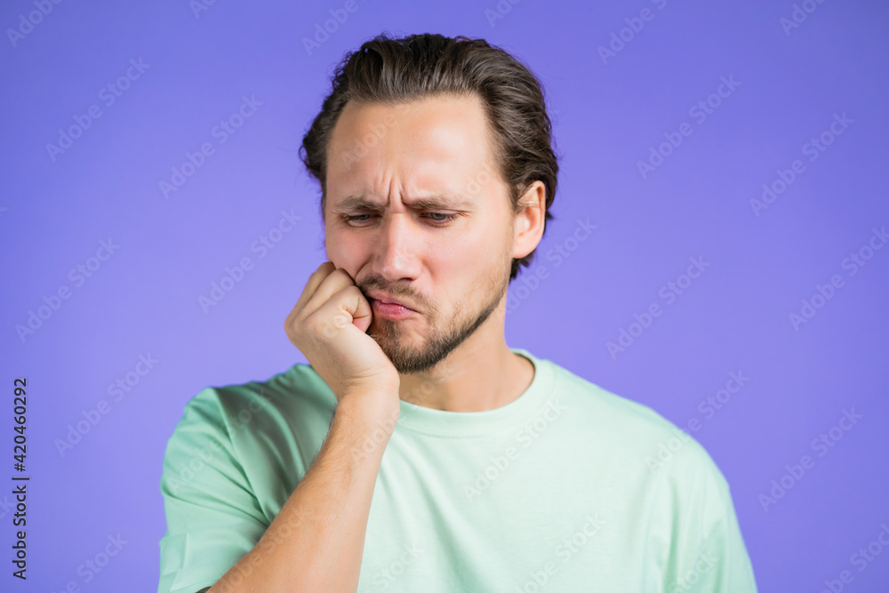 Young handsome man with tooth pain on violet studio background. Toothache, dental problems, stomatology and medicine concept. Young handsome man with tooth pain on violet studio background. Toothache, dental problems, stomatology and medicine concept.