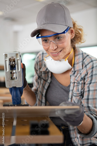 female carpenter using electric sander for wood photo