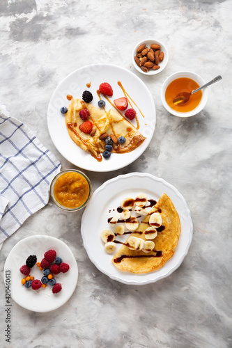 Overhead view of two plates with breakfast crepes, blini