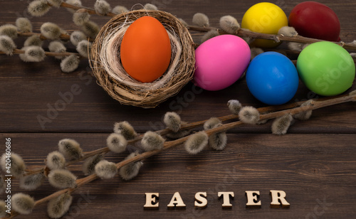 colorful Easter eggs with a willow branch on vintage planks.easter inscription on a wooden background.