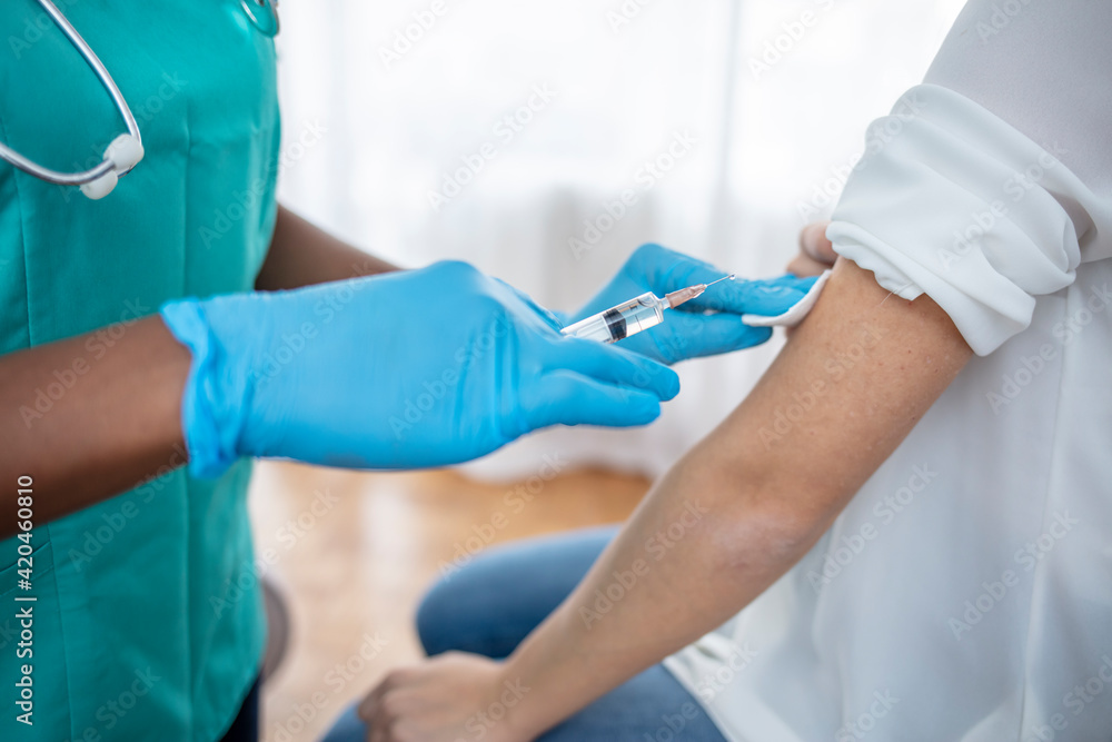 Hands of doctor in medical gloves injecting vaccine to a patient. Doctor giving muscular injection to woman. Vaccination healthcare concept. Selective focus on syringe and vial. Hands of doctor in medical gloves injecting vaccine to a patient. Doctor giving muscular injection to woman. Vaccination healthcare concept. Selective focus on syringe and vial.