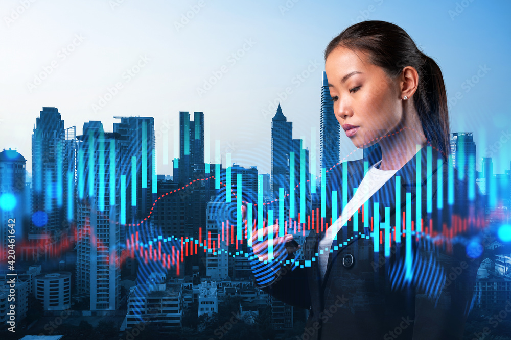 Attractive Asian businesswoman trader checking quotes to forecast the capital market behavior. Concept of trading strategy. Forex chart. Bangkok. Double exposure. - obrazy, fototapety, plakaty 