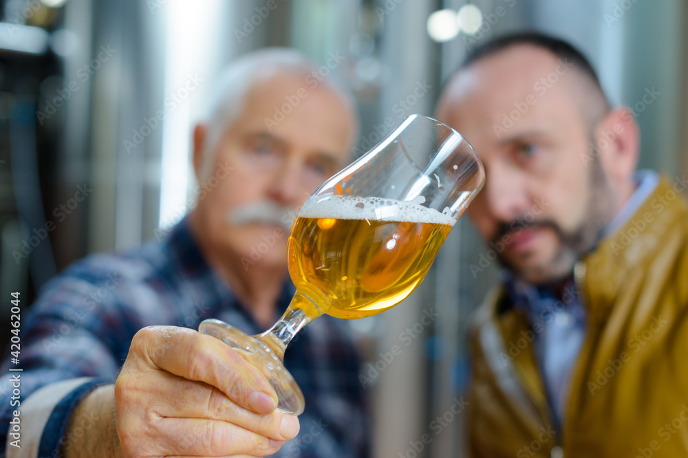 Φωτογραφία brewer tilting glass to inspect beer