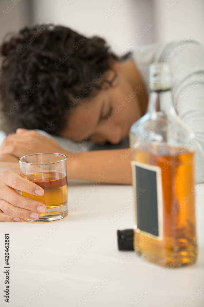 woman slumped over table still holding glass of whisky woman slumped over table still holding glass of whisky