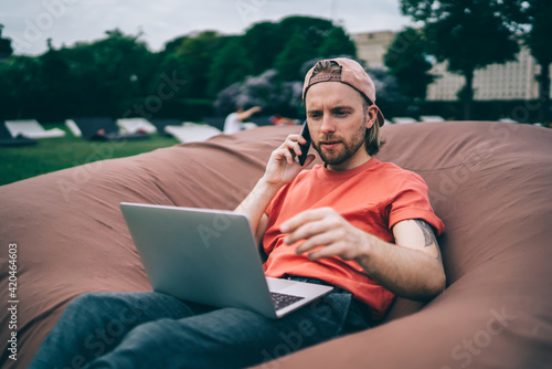 Concentrated freelancer talking to coworker using cellphone in park