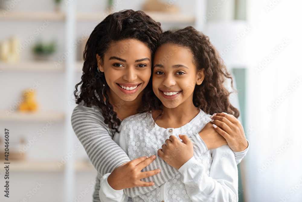 Cute african american school girl hugging her cheerful mother Cute african american school girl hugging her cheerful mother