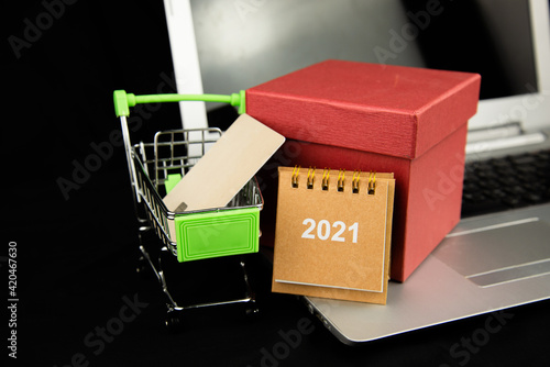 Group object Calendar 2021 and credit card in the shopping cart and red gitf box on laptop with dark background. Business Shopping concept. e-commerce or online shopping concept. new year gift. photo