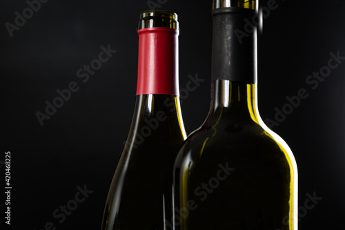 two open bottles of wine stand side by side on a dark glossy background.