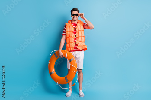 Full length body photo man wearing life vest sunglass ready to swim in the sea isolated on vibrant blue color background