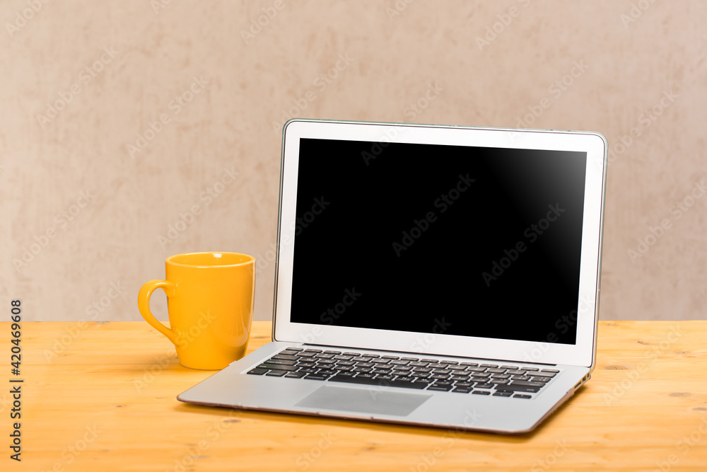 Laptop with blank screen for product display and cup of coffee on wooden table Laptop with blank screen for product display and cup of coffee on wooden table