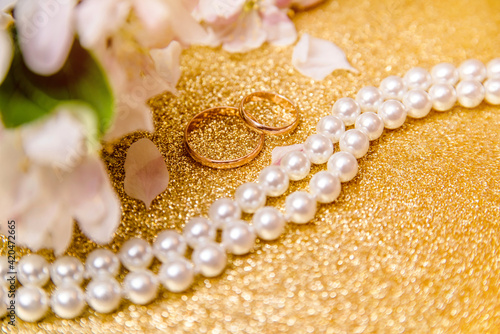 Gold wedding rings and Apple blossoms on a Golden background 