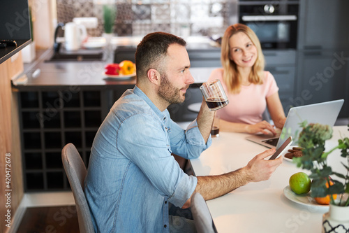 Happy couple drinking coffee and using modern technologies at home