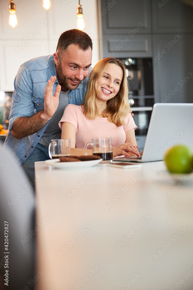 Cheerful couple talking with friend through video call Cheerful couple talking with friend through video call