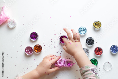 the hands of a little girl, a child who plays with plasticine and jars of sparkles. Child development, fine motor skills, hobbies, classes and home education. High quality photo