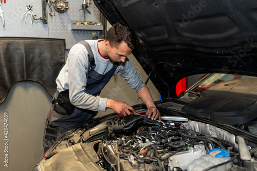 A professional car mechanic is changing an air filter, doing car service and maintenance of the vehicle. Oil and fuel filter changing. Service interval. 