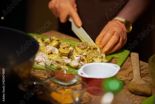 Cooking in the kitchen. cutting meat, wearing gloves