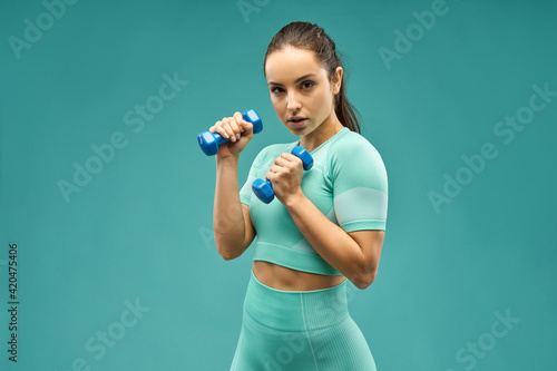 Beautiful sporty woman doing exercise with dumbbells