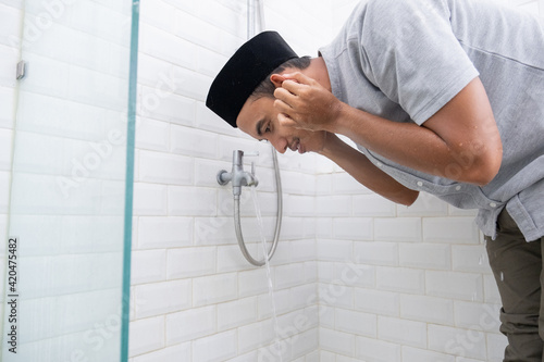 portrait of young Muslim man perform ablution (wudhu) before prayer at home