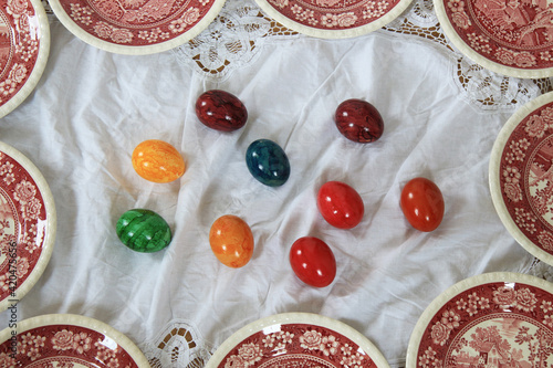 set of red vintage plates on the white lace fabric. Easter eggs in the middle. 
