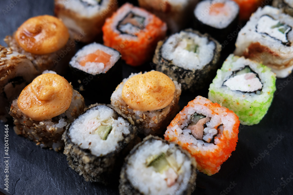 Large sushi set on black. An assortment of various maki, nigiri and rolls Large sushi set on black. An assortment of various maki, nigiri and rolls