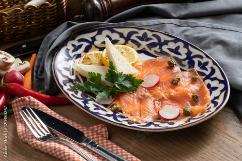 Salmon carpaccio with capers, radish and lemon photo