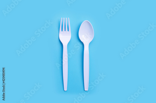 Plastic fork and spoon on blue background.