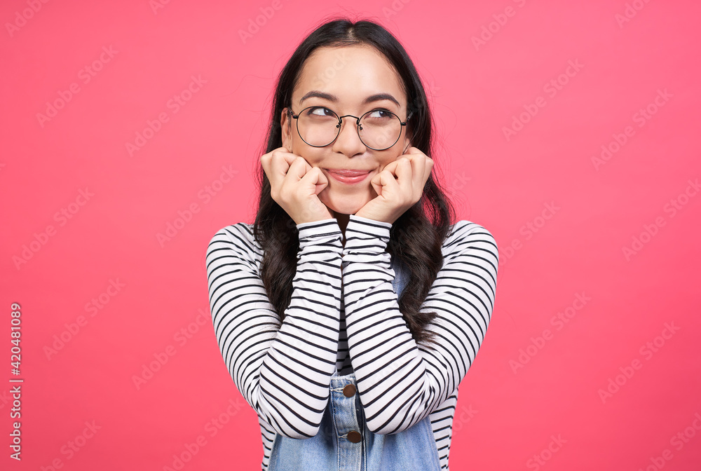 Happy Asian woman holds both hands under her chin and looks to the side. Happy Asian woman holds both hands under her chin and looks to the side.