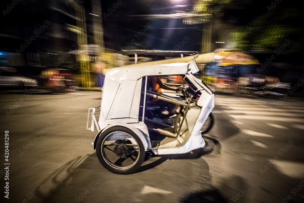 a speeding tricycle in the streets of Metro Manila. The tricycle is a