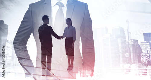 Businessman and businesswoman handshake, double exposure of manager and skyscrapers