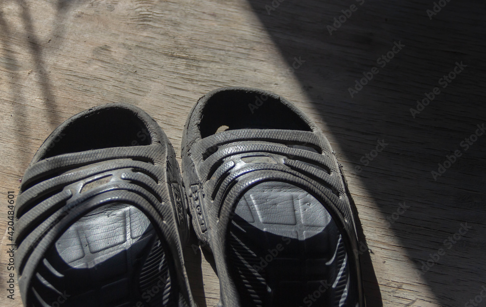 old, worn black sneakers on the floor - obrazy, fototapety, plakaty 