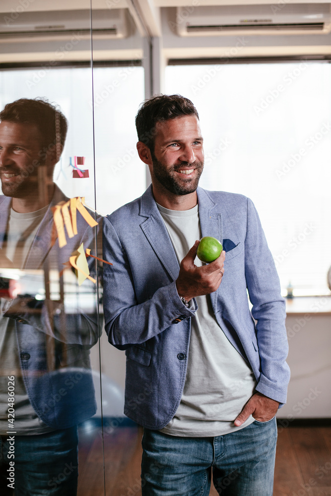 Fototapeta premium Businessman in conference room eating apple. Young businessman having healthy snack.